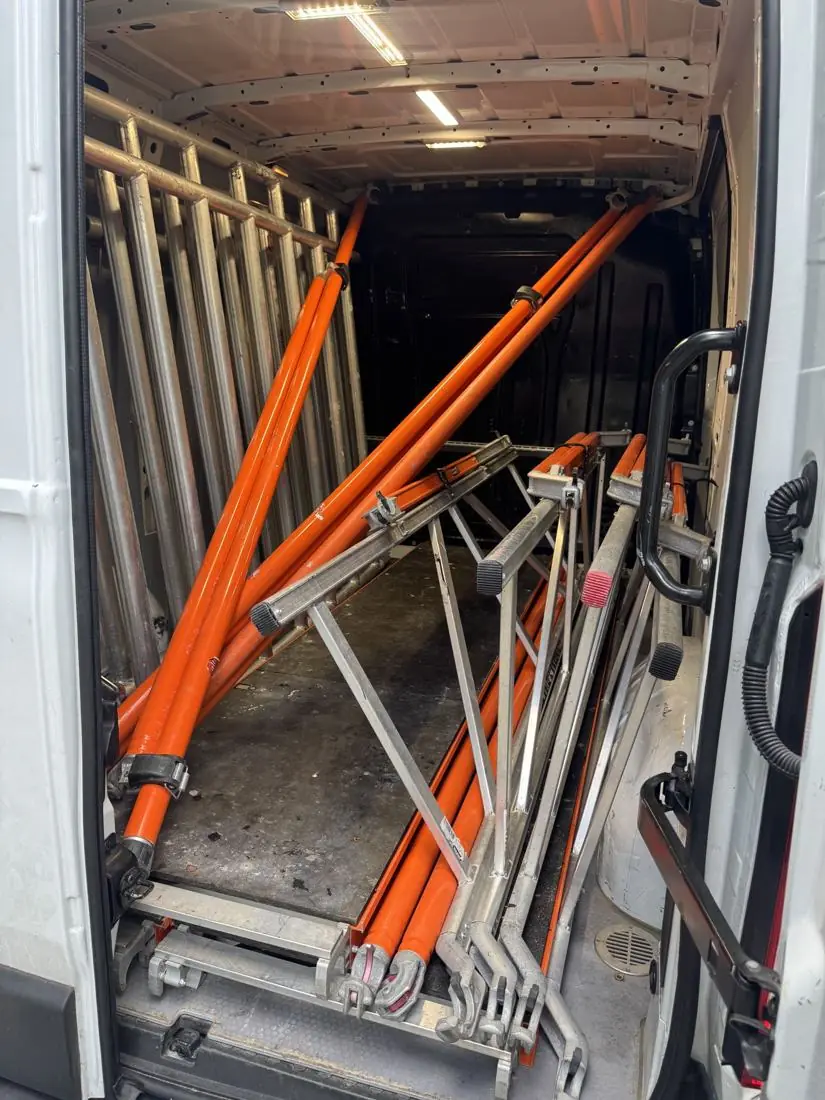 Steigerframes en schoren vastgezet in de laadruimte van de bezorgbus
