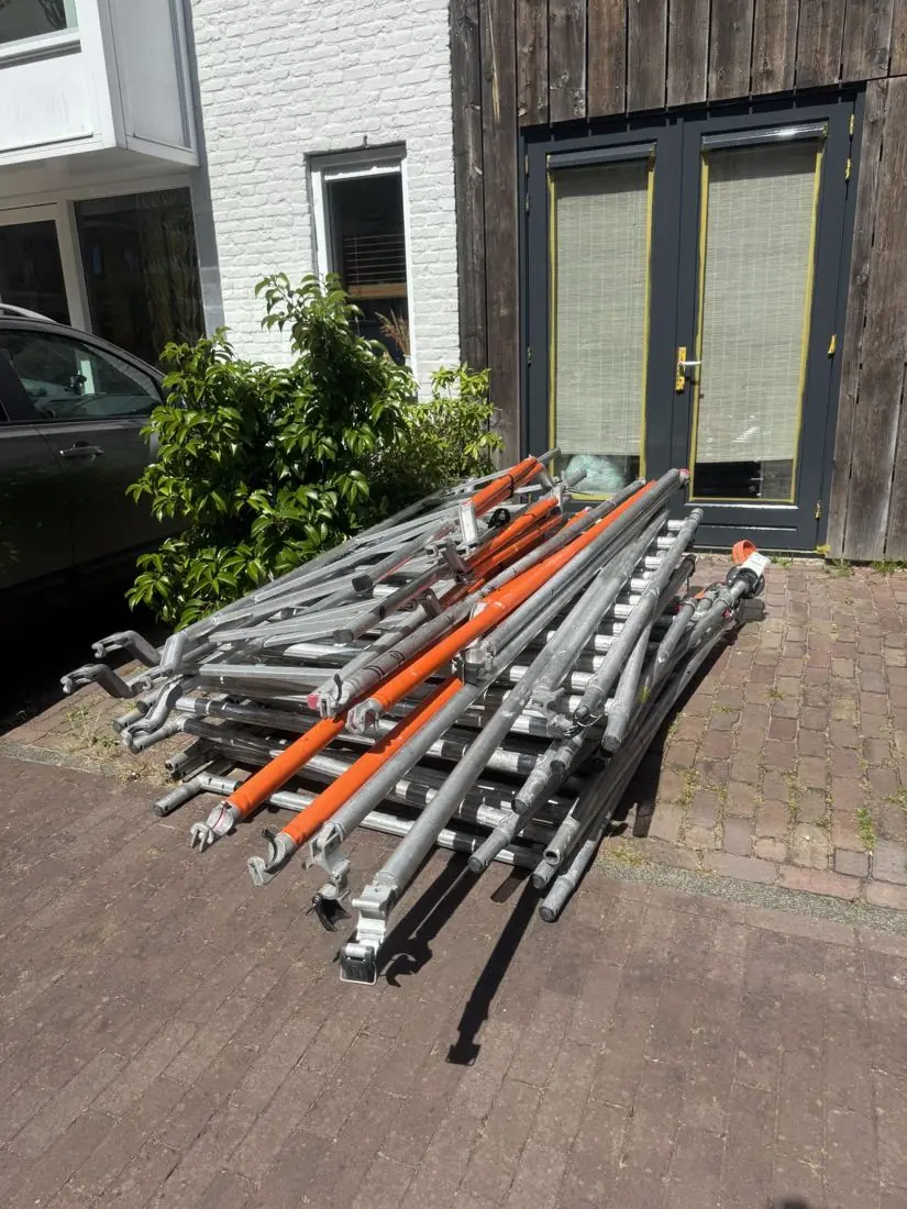 Ingeklapte steigerdelen rechtop tegen de gevel bij de voordeur gezet